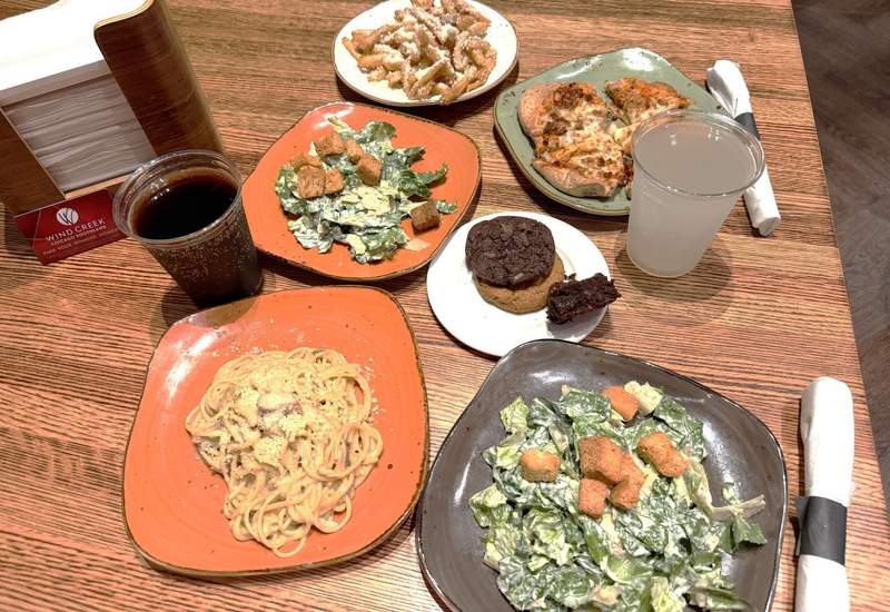 Variety of dishes including pasta caesar salads parmesan fries flatbread and cookies at Food Bazaar at Wind Creek Chicago Southland.