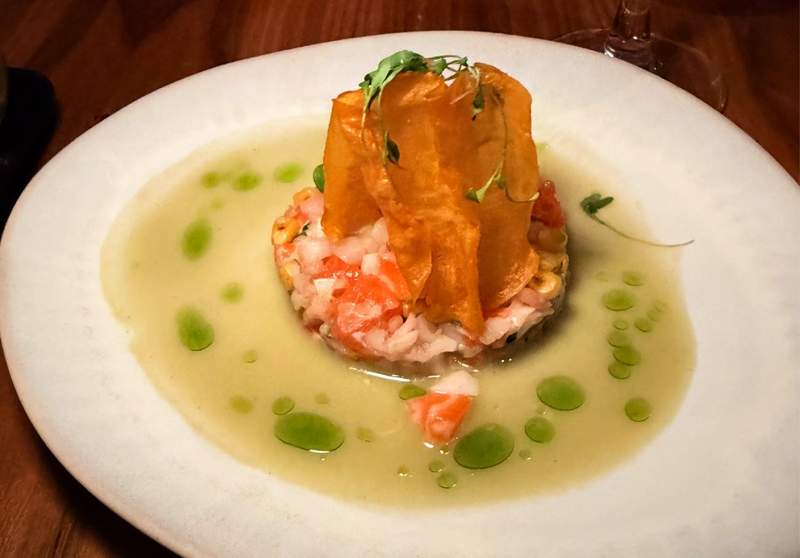 Elegant seafood appetizer at MDRD in Grand Rapids featuring diced seafood, crispy garnish, microgreens, and green herb oil in a delicate sauce.