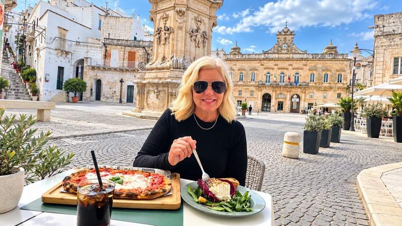 Woman enjoying pizza and a fresh salad at an outdoor café overlooking a historic Italian piazza in Puglia.