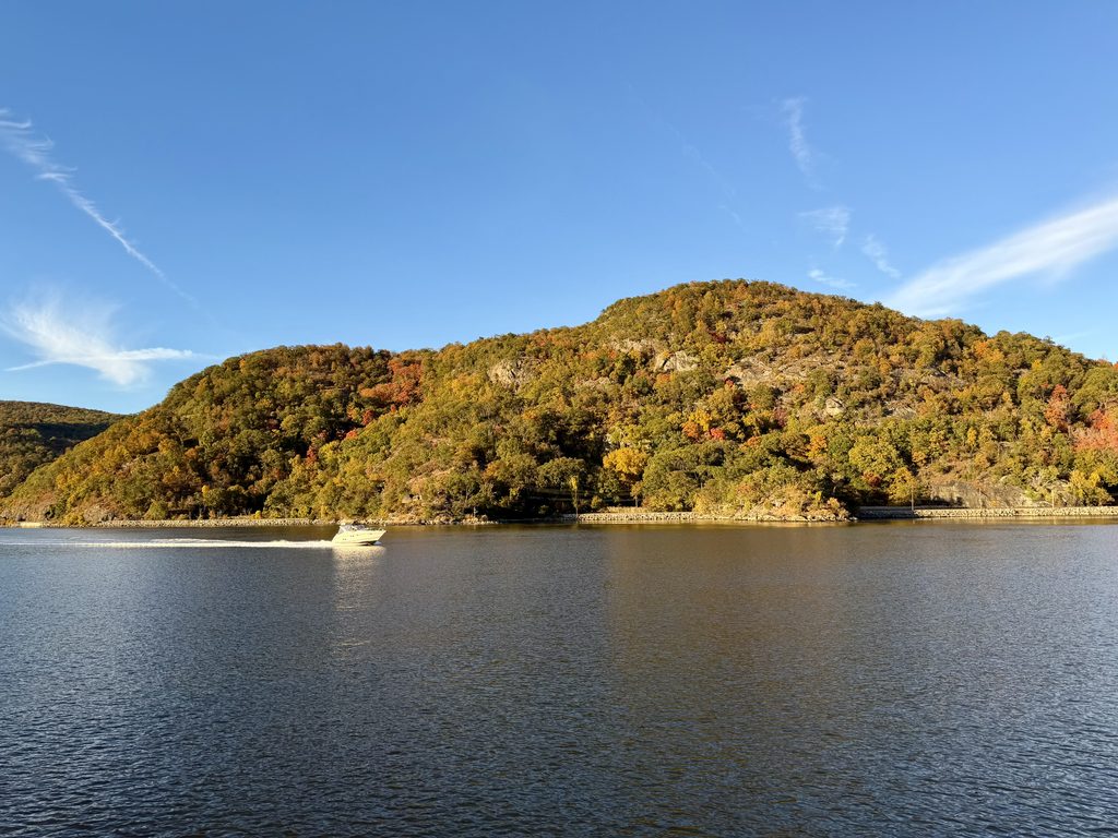 Small boat on the Hudson River with fall colored mountain in the background
