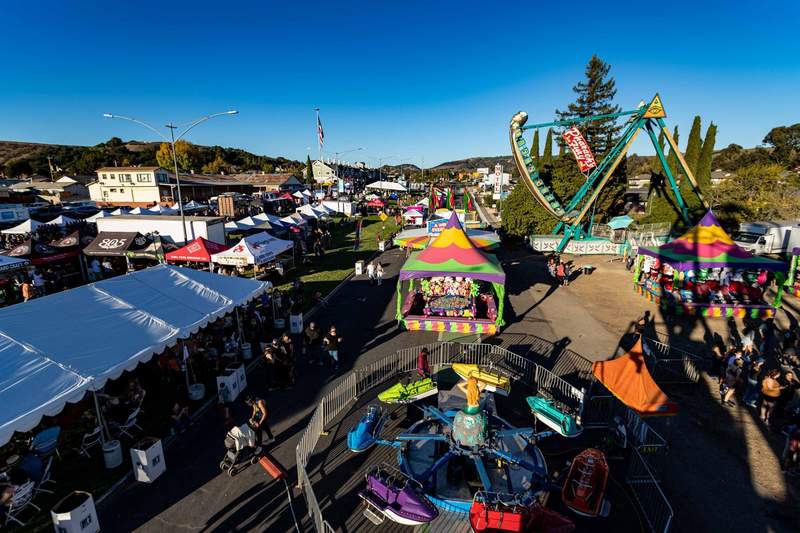 Aerial view of a busy fall festival with craft beer tents, carnival games, a kiddie jet ski ride and a swinging boat ride