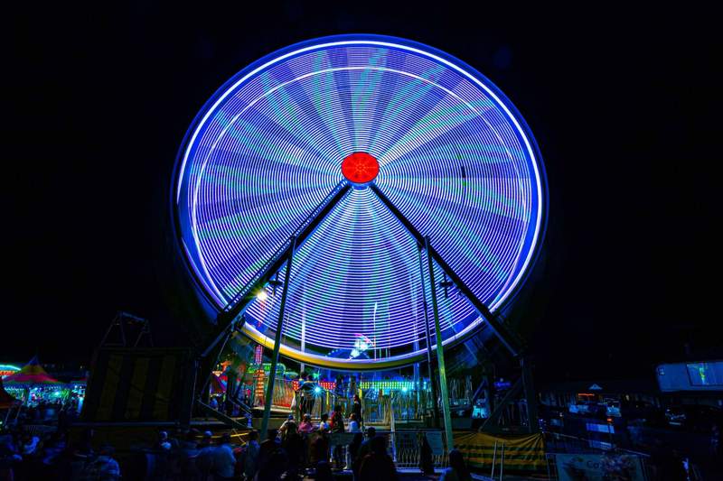 Long exposure of a spinning Ferris wheel glowing blue 