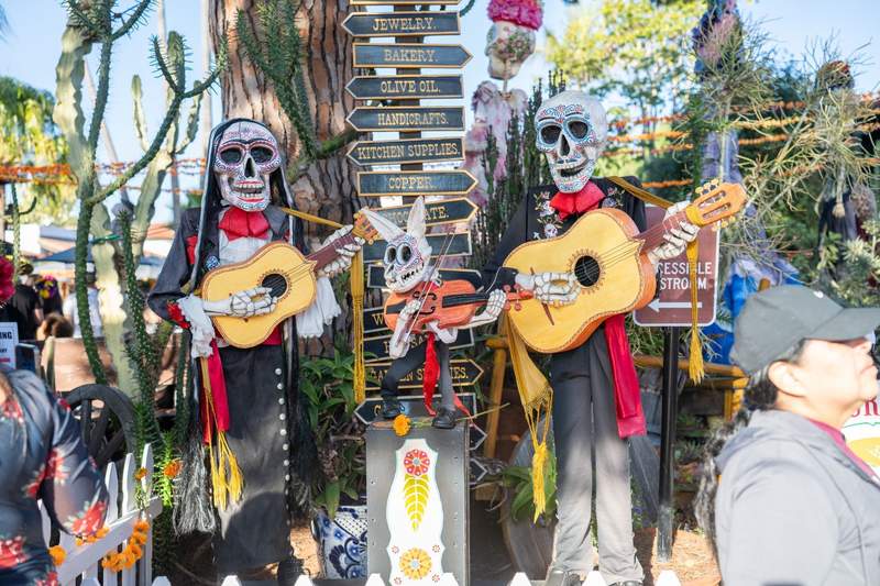 Sugar skull skeleton mariachis playing guitars beside a rabbit skeleton violinist among cactus and marigold garlands in Old Town San Diego